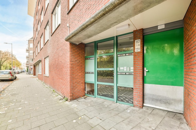 Photo a brick building with a green door on a sidewalk