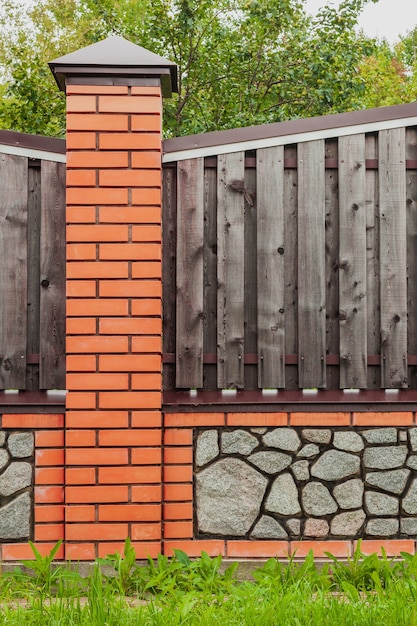 Кирпичный забор с деревянными пролетами и серым гравием
