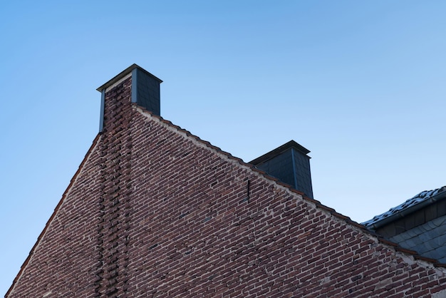 Photo brick part of the facade and roof of an old building under the blue sky