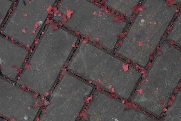 A brick sidewalk with red petals on it