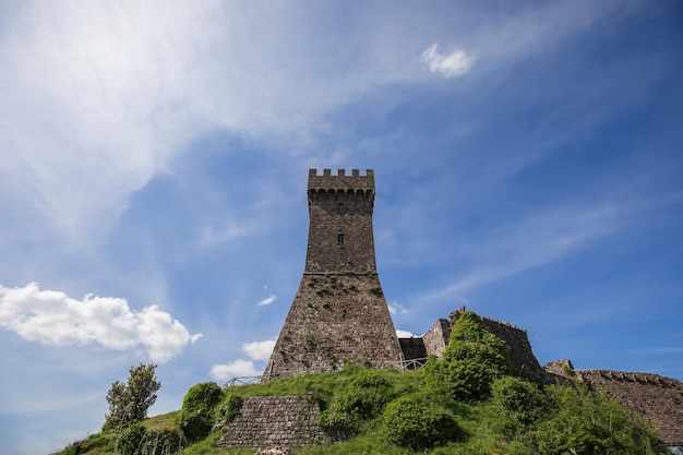 여름날 Tuscany, Italy, Val d'Orcia에 흐린 하늘을 배경으로 Radocofani의 벽돌 탑 Rocca