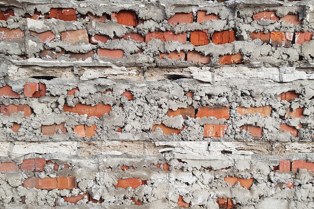 Brick wall behind a layer of falling off cement or concrete