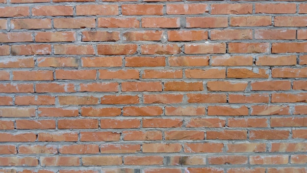 Brick wall of redorange bricks and blocks Lightly worn surface Neat masonry cement between the rows Grunge background Building Exterior or Room Interior Wide angle Vintage Red brick wall