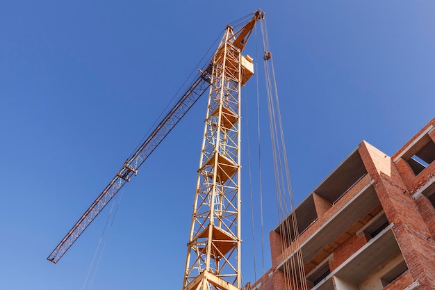 Brick wall and tower crane background of blue sky