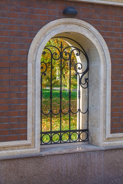 A brick wall with an arch and an iron lattice