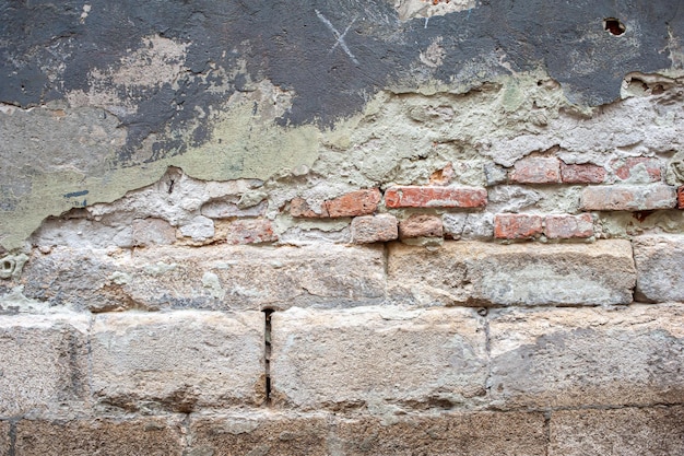 A brick wall with a red brick and a white cross on it.