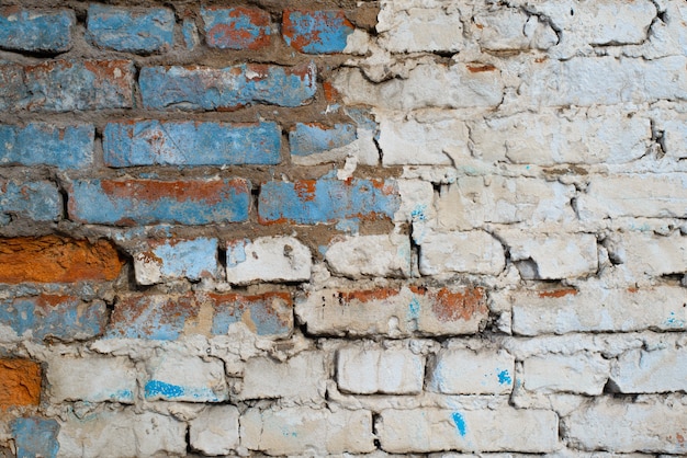 Brick wall with white and blue paint outdoors. Old, cracked horizontal brickwork with copy space for text. Textured grunge background