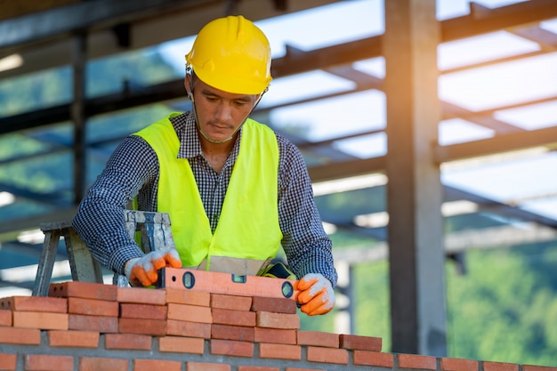 Bricklayer laying bricks to make a wall at construction site.