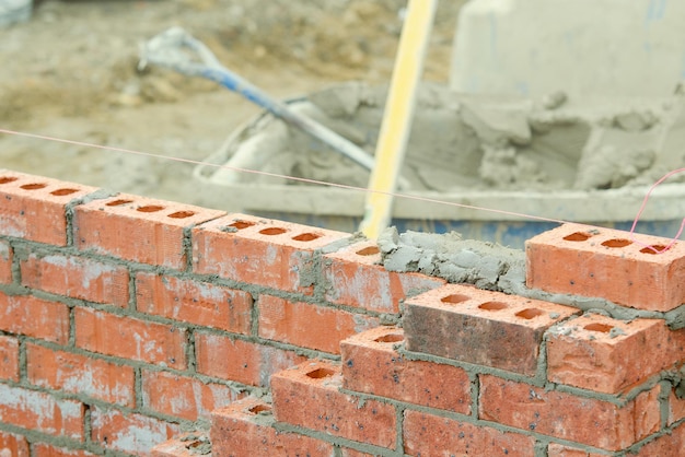 Bricklayer laying bricks on mortar on new residential house construction