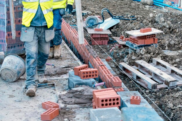 bricklayer laying concrete blocks on top of concrete foundation on new residential housing site