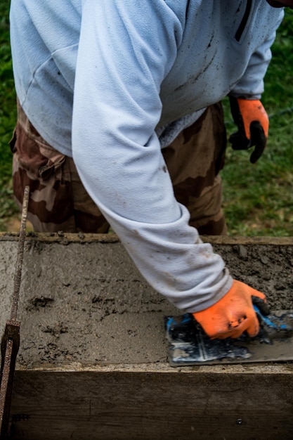 Bricklayer spreading concrete with a trowel and level to build a wall at a construction site