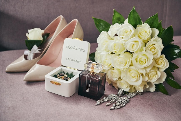 Bridal accessories such as shoes bouquet ring and perfume lie on a table