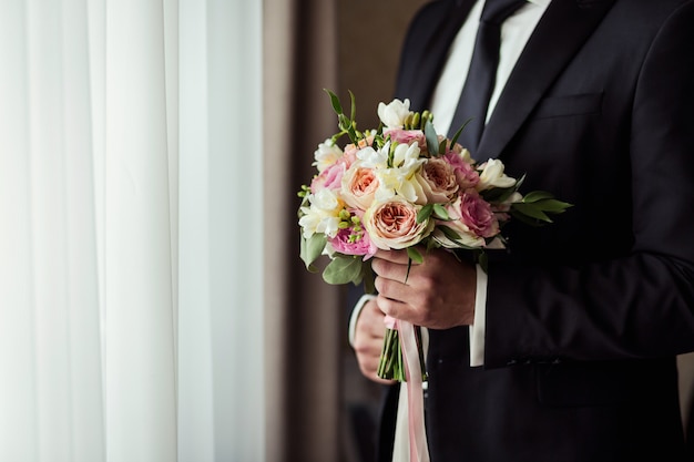 Bridal bouquet in hands, wedding bouquet in hands of the groom, groom morning, businessman, wedding, man's fashion, man's style