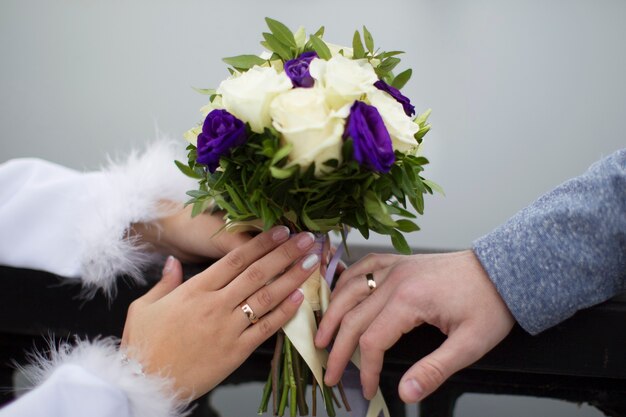 Bridal bouquet and hands with wedding rings. The bride's bouquet. Wedding rings.