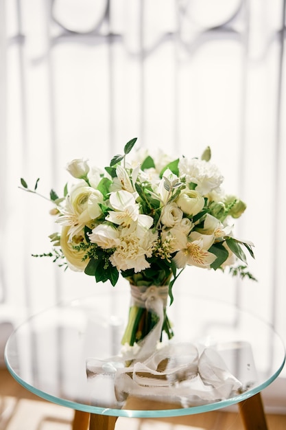 Bridal bouquet stands on a glass table in a room