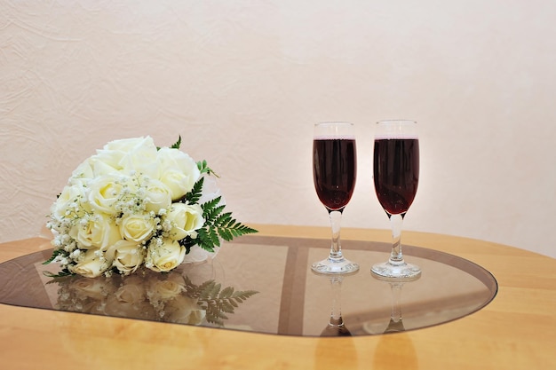 Bridal bouquet and two glasses of wine on the table