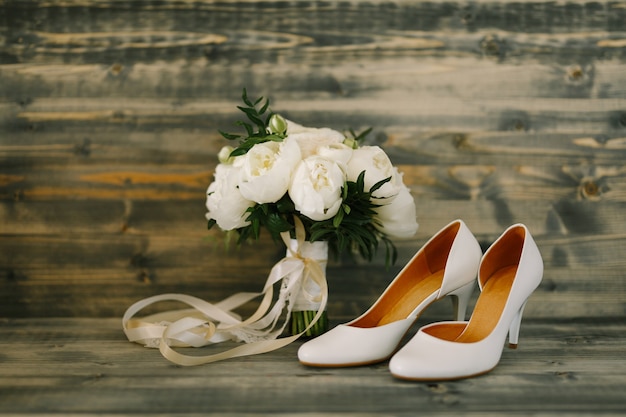 Bouquet da sposa e scarpe da sposa su uno sfondo di legno