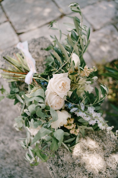 Bridal bouquet of white and cream peonies roses veronica delphinium branches of eucalyptus tree with