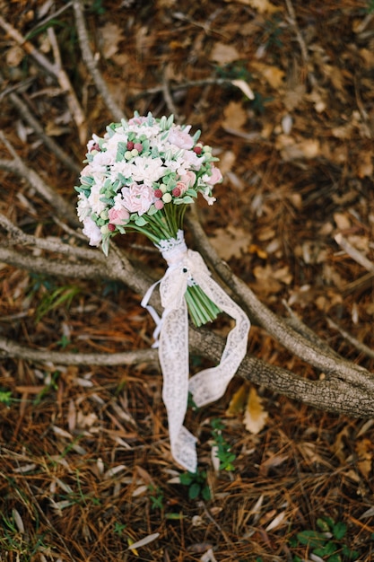 Foto bouquet da sposa di rose bianche e rosa bacche selvatiche eustoma con nastri di pizzo bianco sull'asciutto