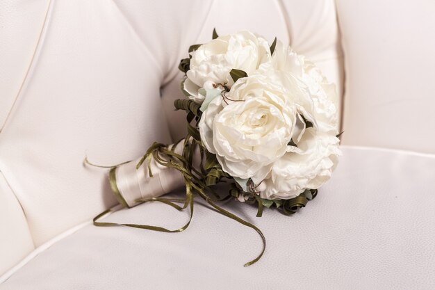 Bridal bouquet of white rose in bright colors on white leather