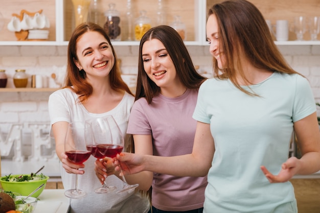 Addio al nubilato. divertimento e festa. giovani donne felici che si congratulano con l'amico. bicchieri di vino rosso che tintinnano.