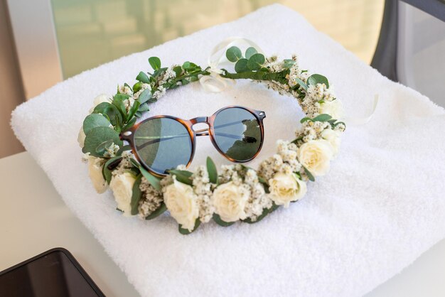 bridal wreath made of natural flowers and sunglasses on a towel in a spa