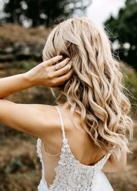 Невеста поправляет свои волнистые волосы, носить обручальное кольцо