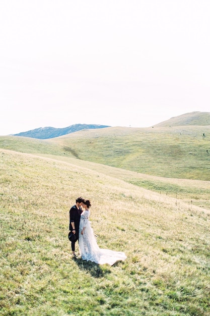 신부와 신랑은 산을 배경으로 푸른 잔디 위에 서 있다