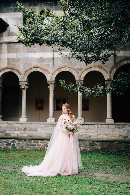 Bride in a beautiful dress with a bouquet of flowers in a green garden