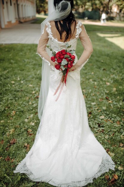 A bride in a beautiful dress with a train holding a bouquet of flowers and greenery.