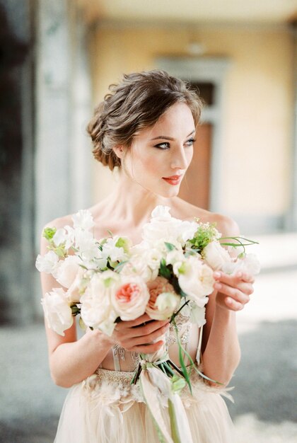 Bride in a beige lace dress with a bouquet of flowers