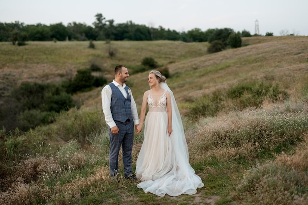 Bride blonde girl and groom in a field