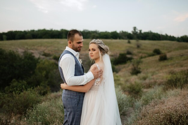 Bride blonde girl and groom in a field