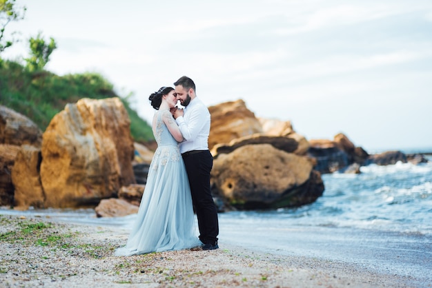 bride in a blue dress walk along the ocean shore