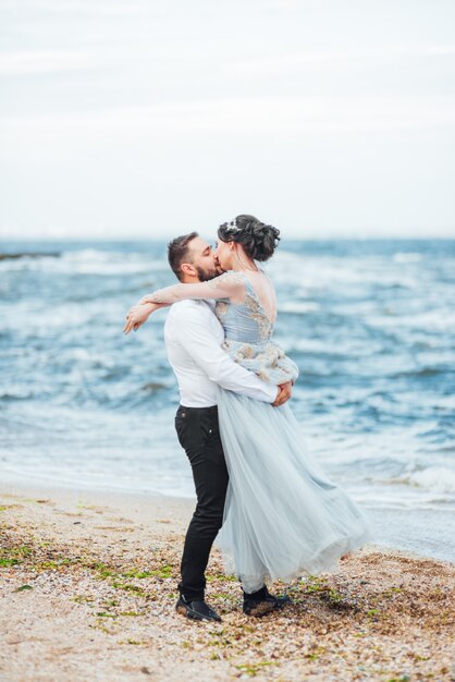 bride in a blue dress walk along the ocean shore