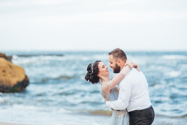 bride in a blue dress walk along the ocean shore