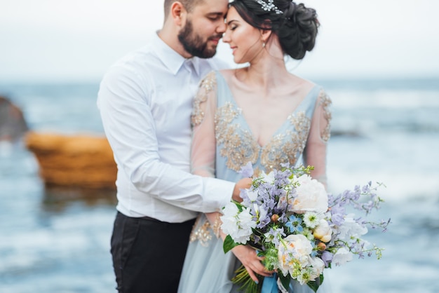 bride in a blue dress walk along the ocean shore