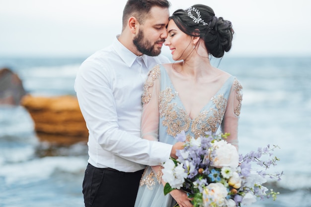 bride in a blue dress walk along the ocean shore