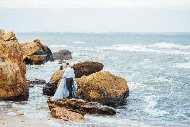 bride in a blue dress walk along the ocean shore