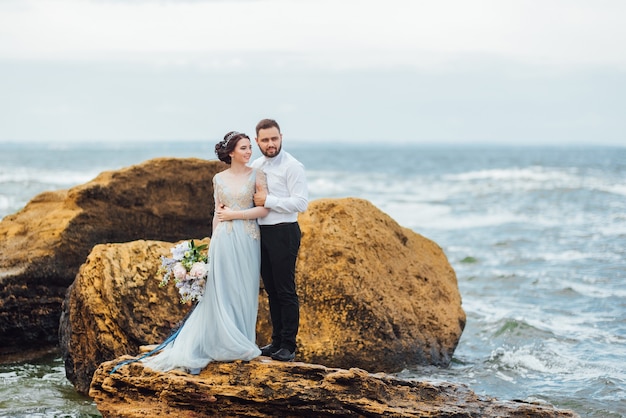 bride in a blue dress walk along the ocean shore