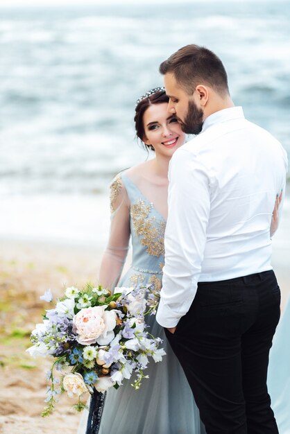 bride in a blue dress walk along the ocean shore