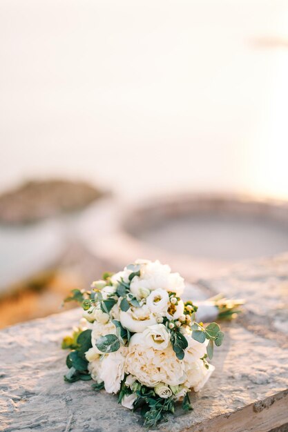 花嫁の花束は太陽の下の石のフェンスに横たわっている