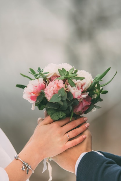Невеста и невеста, держась за руки с букетом цветов свадьбы