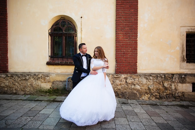 Sposa e sposo che camminano attraverso la strada acciottolata