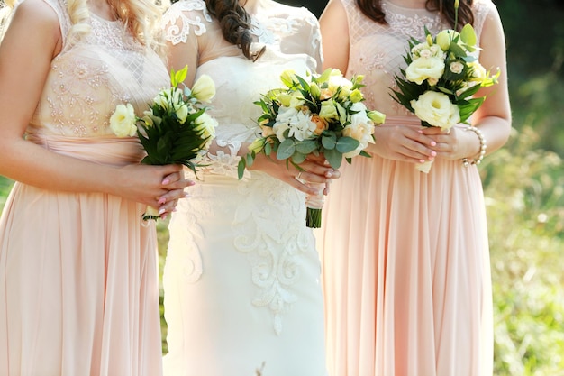 Bride and bridesmaids holding with wedding bouquets on their hands