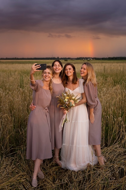 Foto sposa e damigelle d'onore che prendono selfie a tutto campo