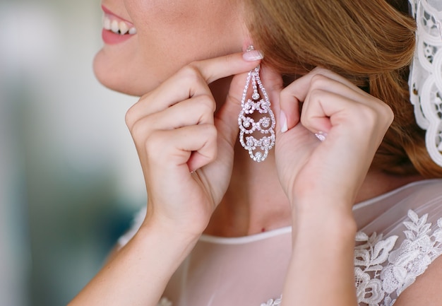 The bride corrects the earring, Beautiful earrings and hands of the bride