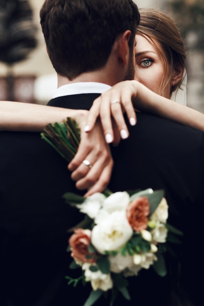 Bride crosses her tender hands on groom's back