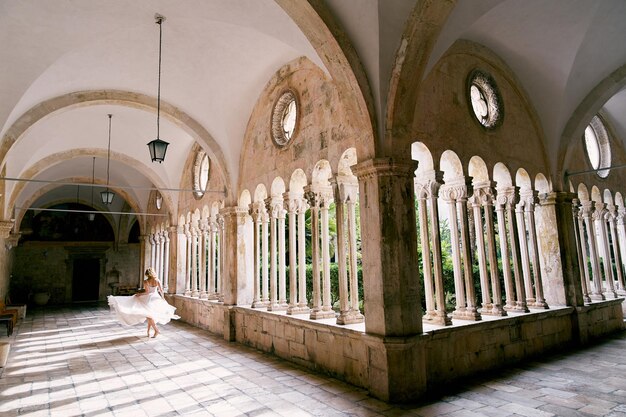 Photo bride dances in the arched gallery of the franciscan monastery dubrovnik croatia back view