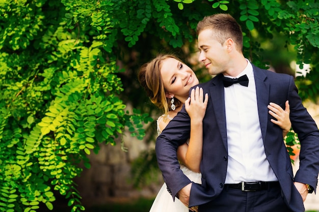 The bride embraces her groom in a beautiful suit and bow tie on